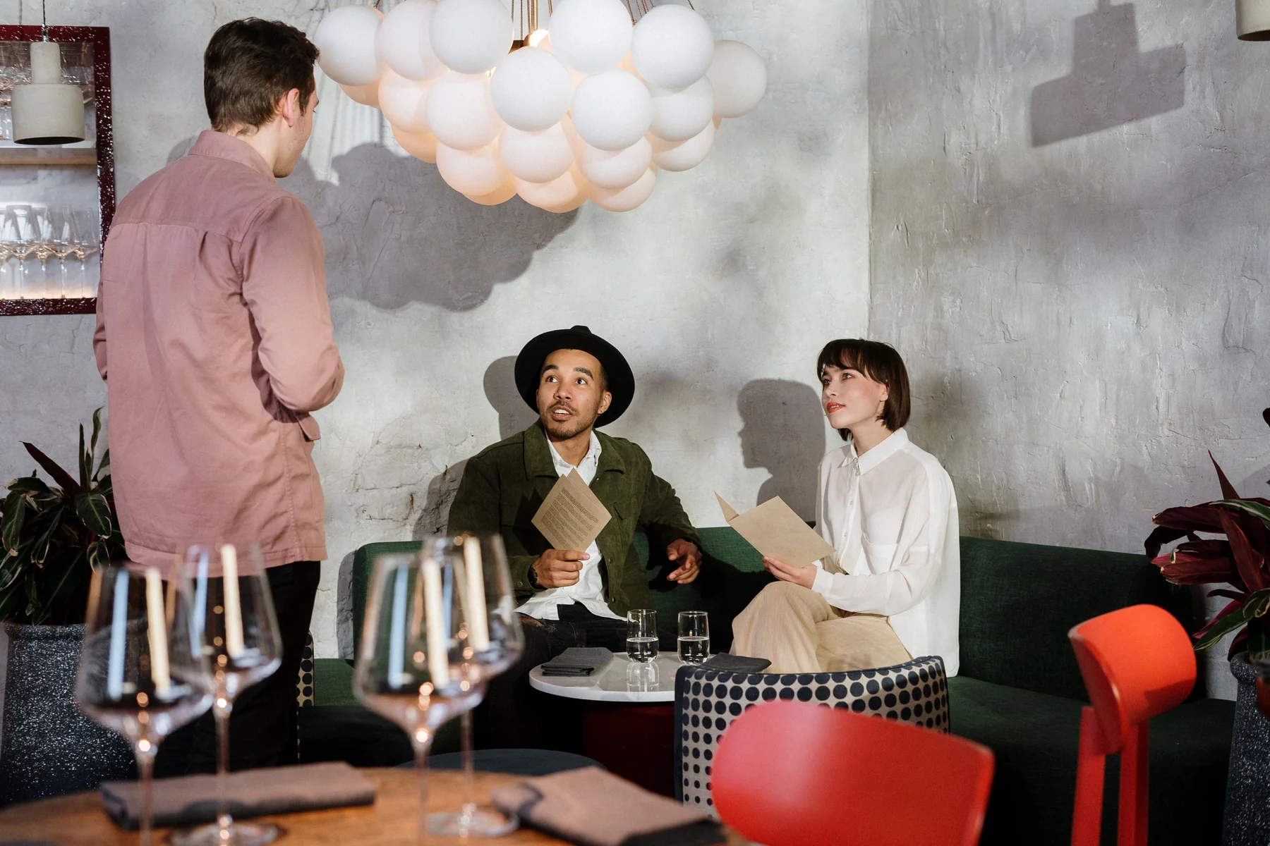 Restauranggäster tittar på menyer och pratar med en servitör.
